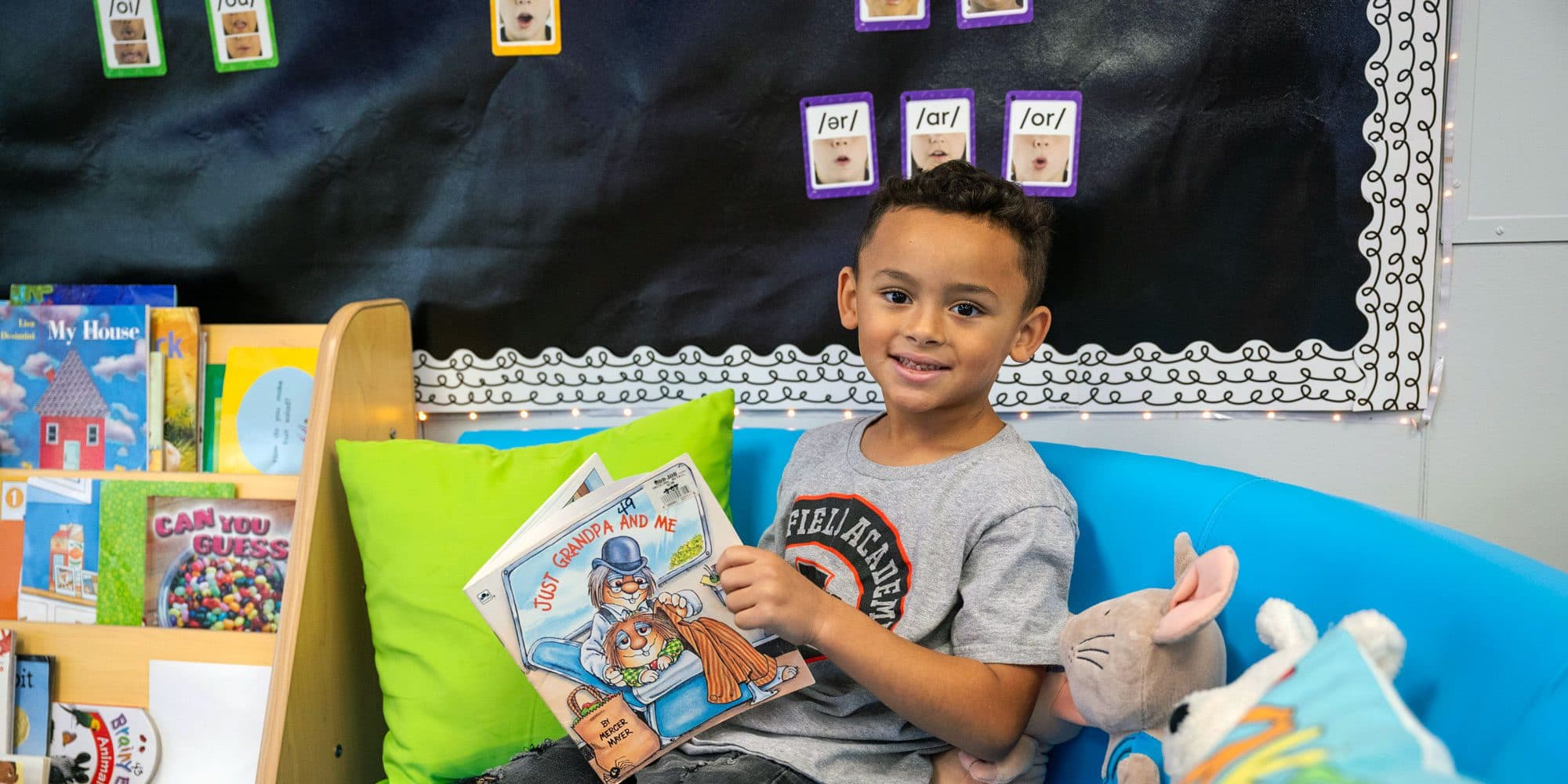 Young student smiling while holding an open book.