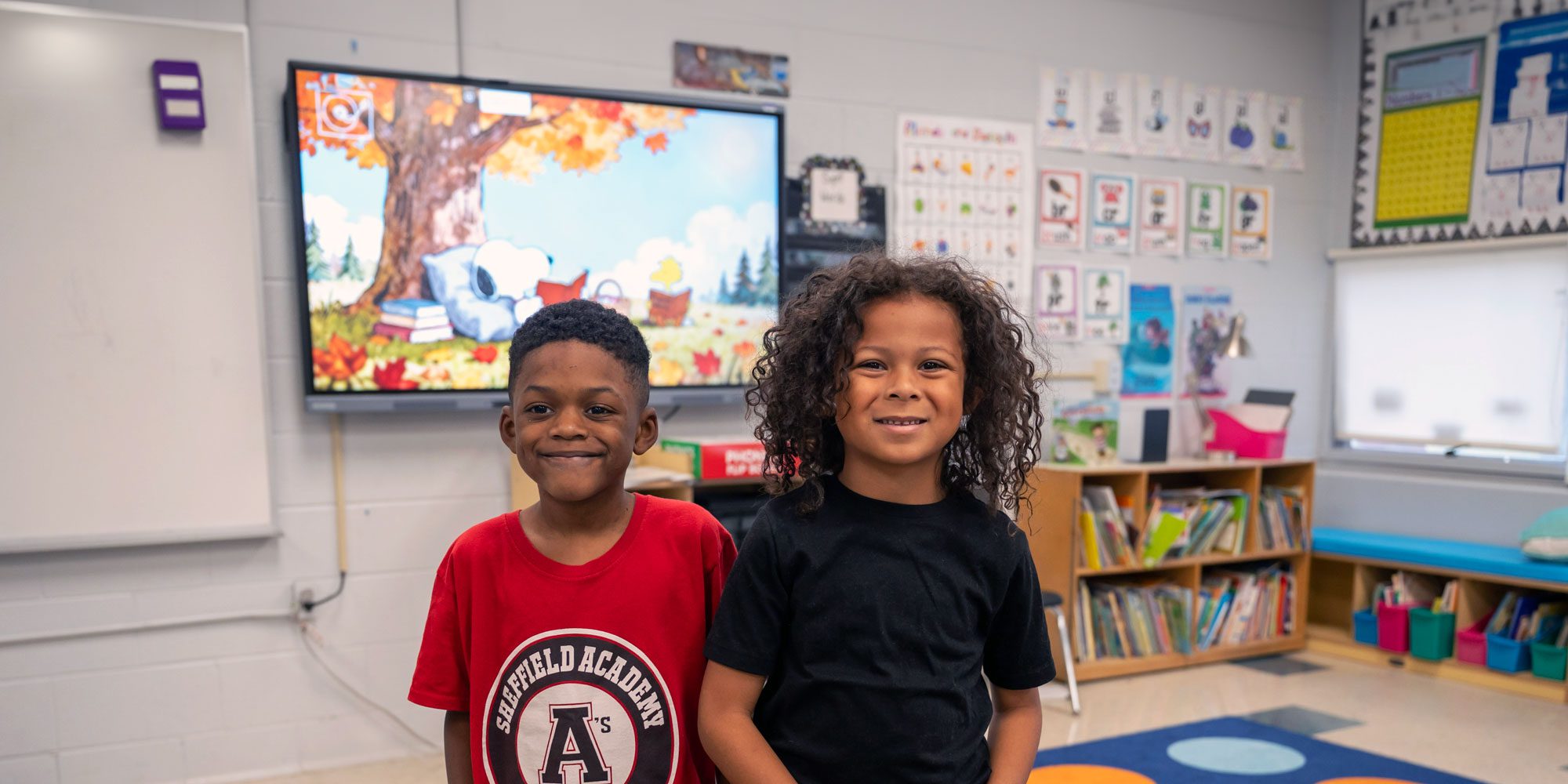 Two smiling students in a classroom.