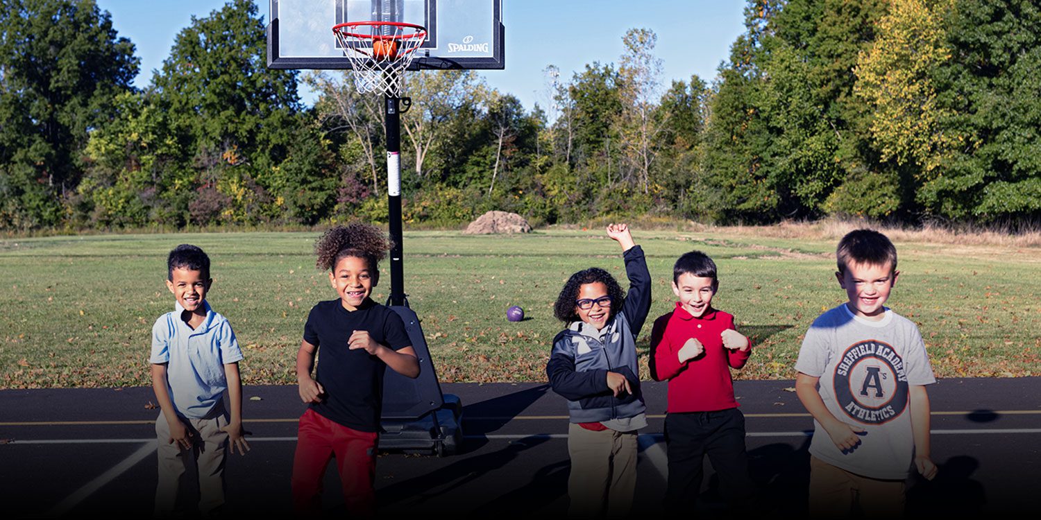 Group of smiling students dancing on the basketball court